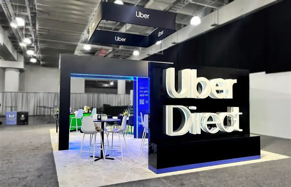 A large, experiential booth including a wooden framed structure with letters on it that say "Uber Direct."