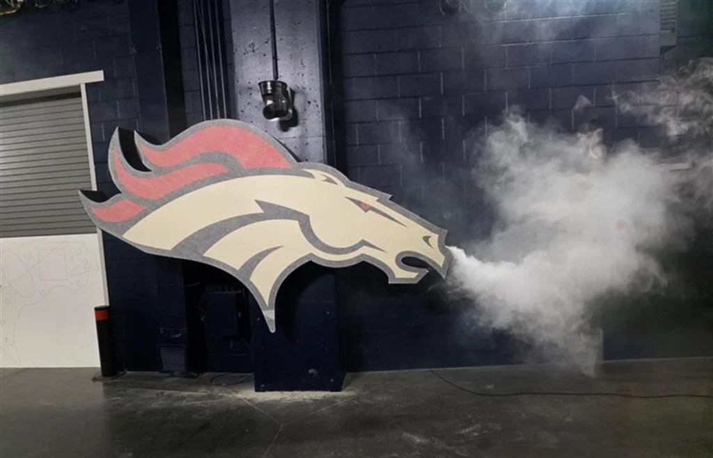 A metal fabrication of the Denver Broncos logo featuring a smoke machine hidden in the nostril.