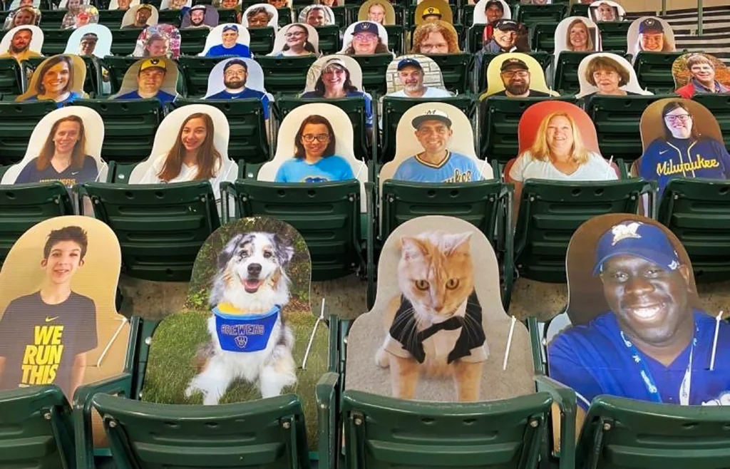 Cutouts on rigid boards of pets and people inside a stadium.